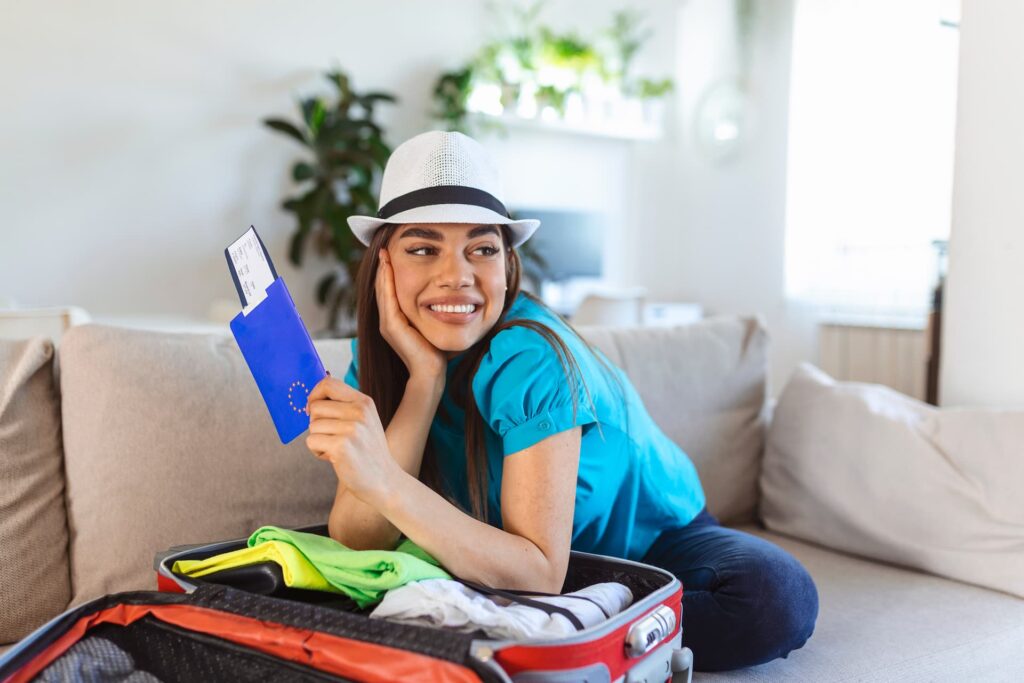 Smiling woman with a suitcase holding a passport, symbolizing Kiwis planning dental tourism and holiday travel.