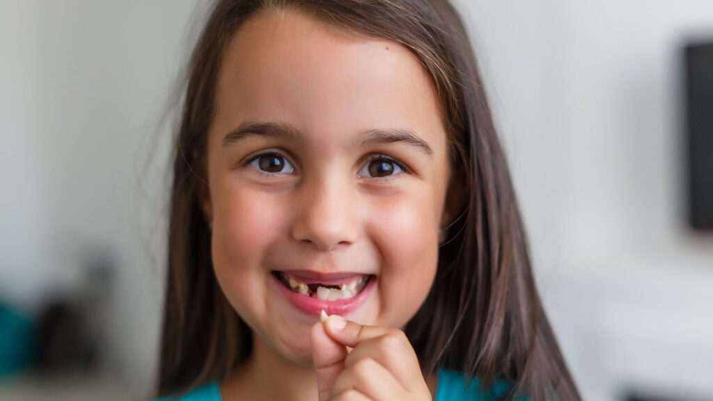 Girl holding lost tooth before her first dental visit with a dentist in Christchurch.