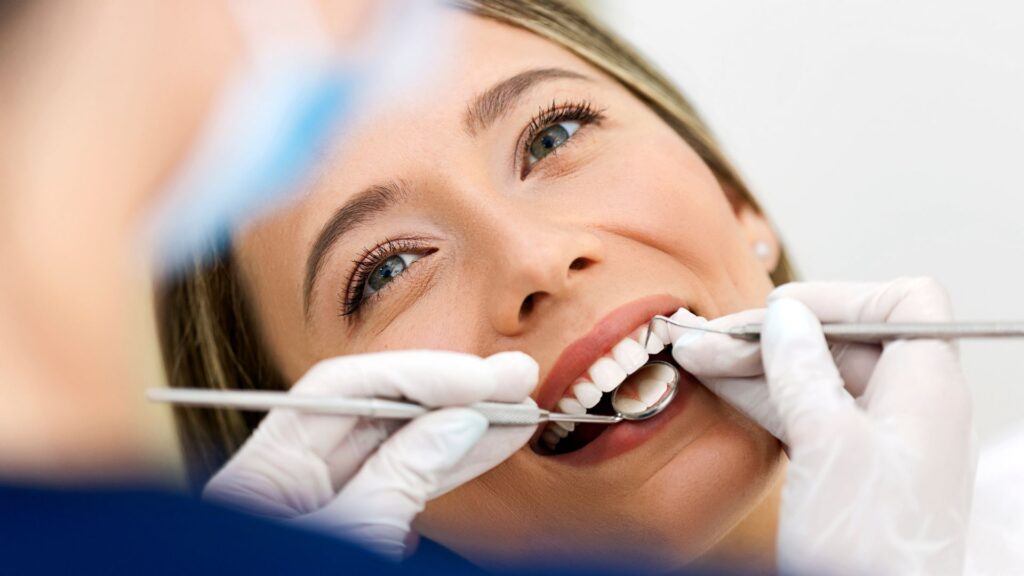Smiling woman undergoing a dental check-up with tools in her mouth, illustrating a calm experience with Dental Sedation.